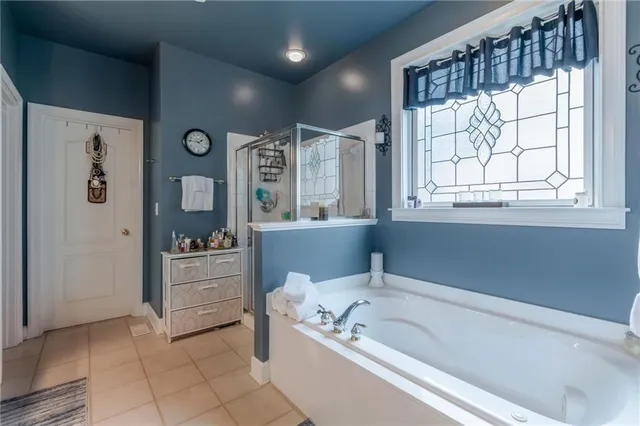 a bathroom with a bathtub a mirror a window and a shower