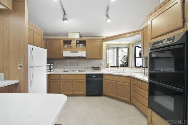 a kitchen with stainless steel appliances granite countertop a refrigerator and a stove top oven