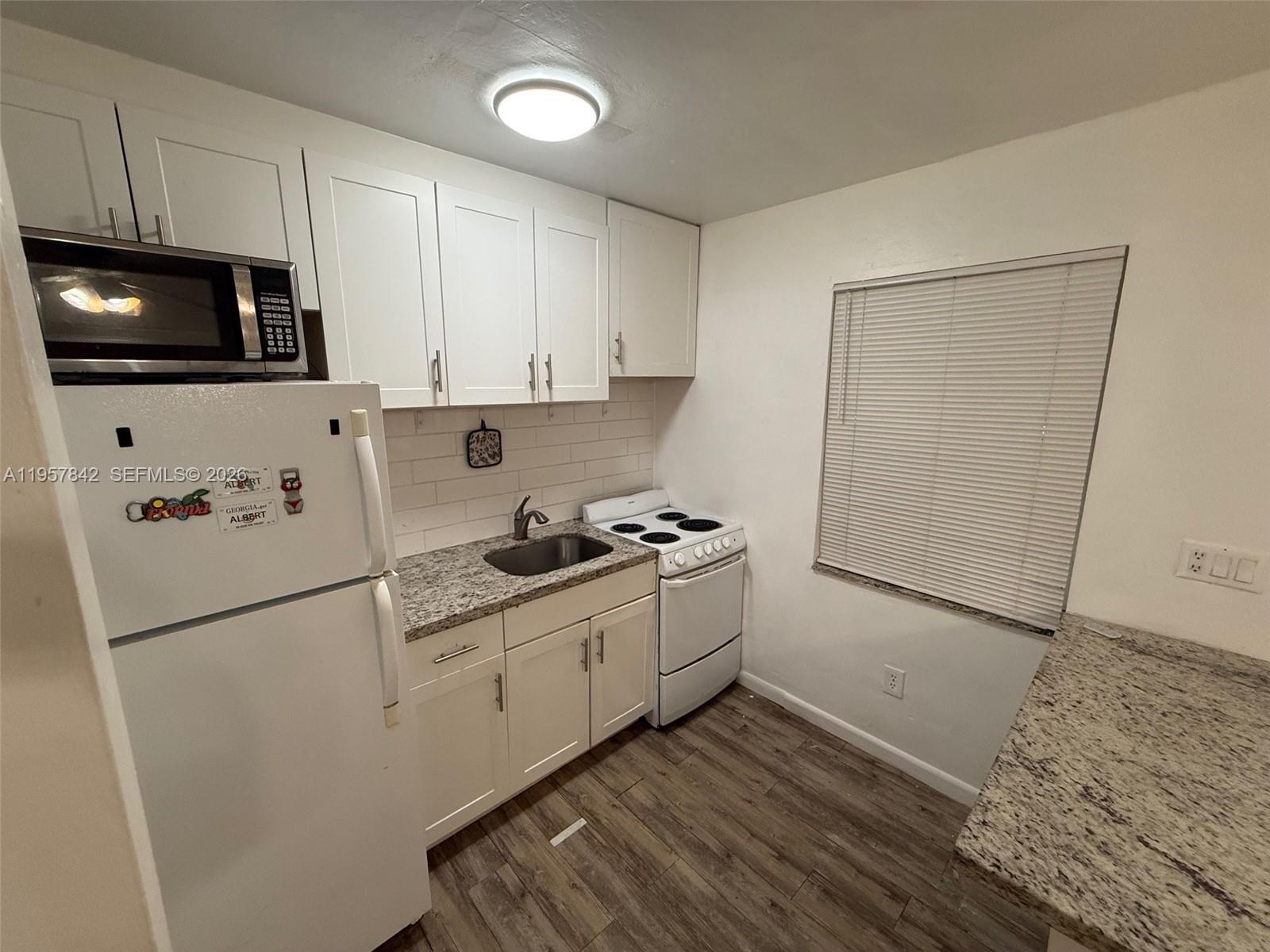 34 Southwest 5th Street, Unit 2 Hallandale Beach, FL 33009 - Photo 4 of 12 a kitchen with stainless steel appliances a sink a stove a microwave and cabinetry