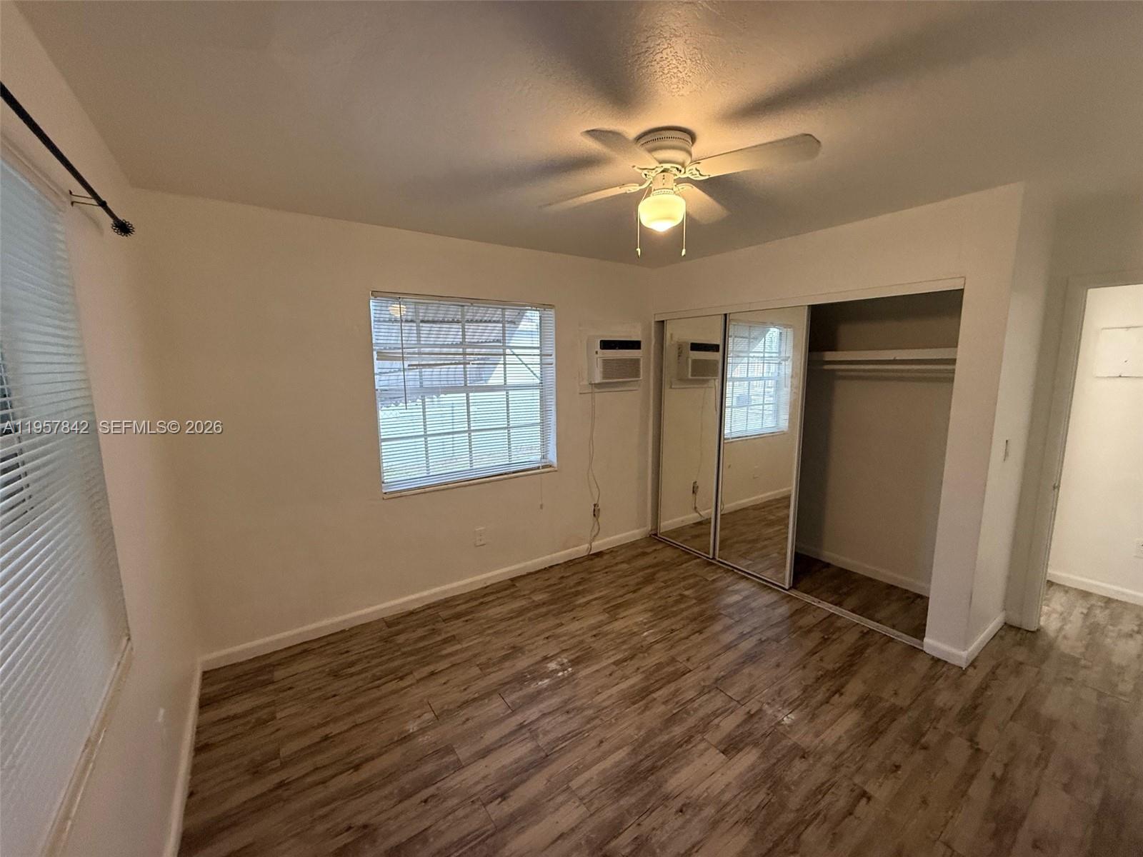 34 Southwest 5th Street, Unit 2 Hallandale Beach, FL 33009 - Photo 6 of 12 an empty room with wooden floor fan and windows
