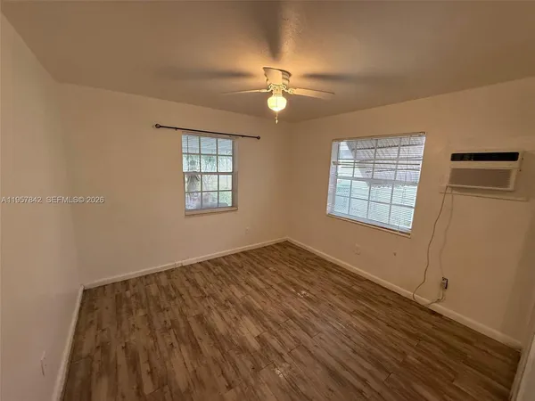 a view of empty room with wooden floor and fan