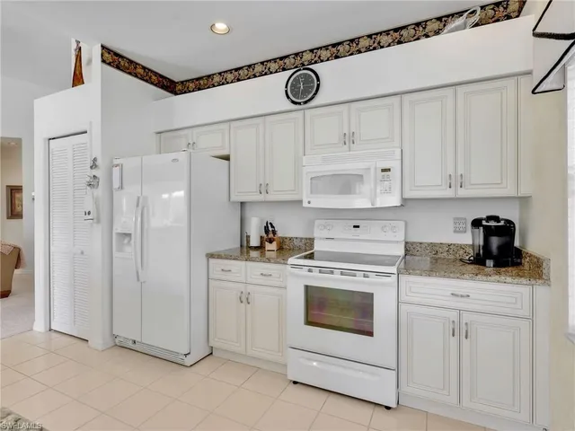 a kitchen with white cabinets and white appliances