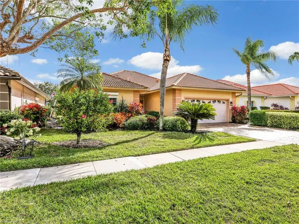 a view of a house with a yard and palm trees