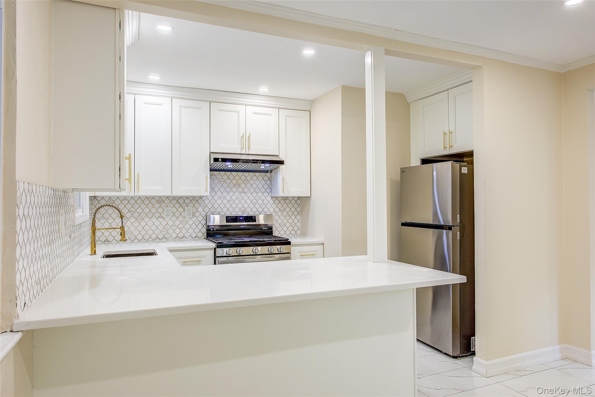 164-38 76th Road Queens, NY 11366 - Photo 9 of 44 a kitchen with kitchen island a refrigerator and a stove top oven