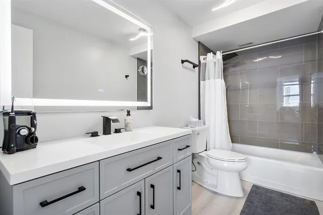 a bathroom with a sink a toilet a mirror and shower