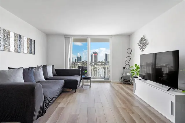 a living room with furniture a flat screen tv and a floor to ceiling window