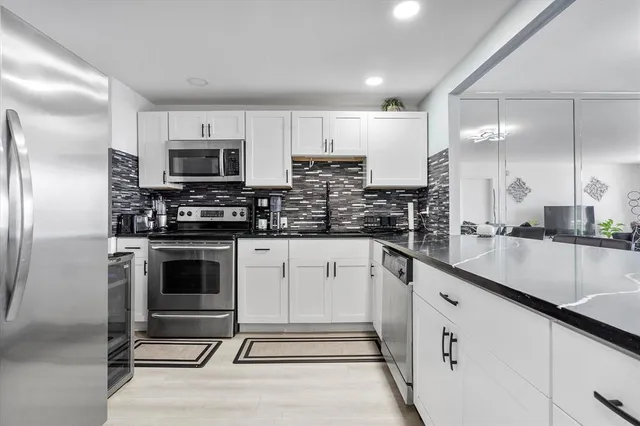 a kitchen with stainless steel appliances granite countertop a stove a sink and a refrigerator