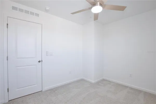 an empty room with a fan & a ceiling fan