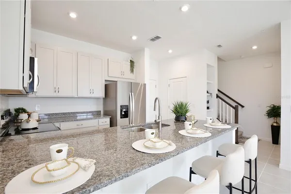 a kitchen with stainless steel appliances kitchen island granite countertop a sink a stove a dining table and chairs