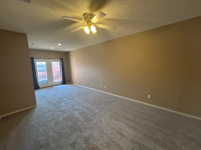 an empty room with windows and chandelier fan