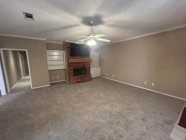 an empty room with fireplace and a ceiling fan