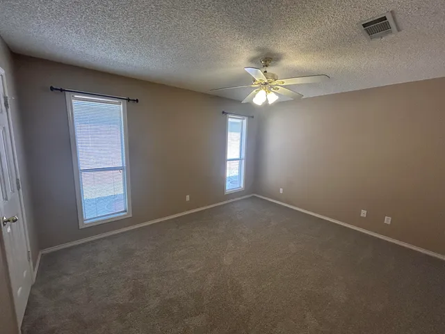 an empty room with windows and fan