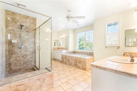 a spacious bathroom with a granite countertop sink a mirror a bathtub and shower