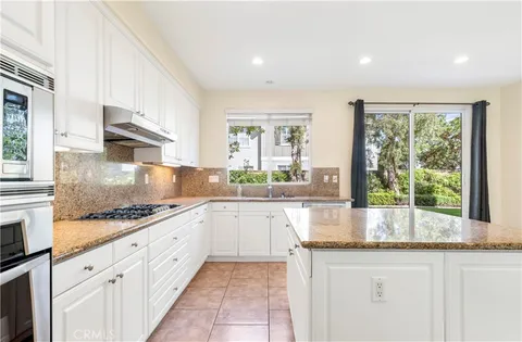 a kitchen with granite countertop stainless steel appliances a stove sink and cabinets