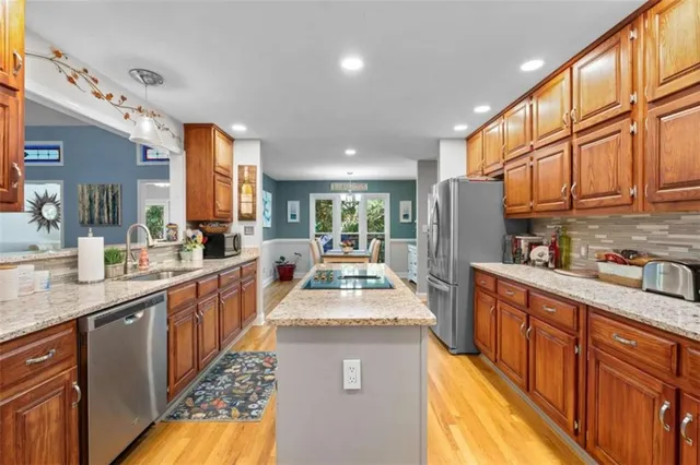 a large kitchen with stainless steel appliances granite countertop a refrigerator a sink dishwasher and wooden cabinets with wooden floor