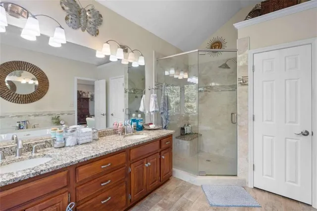 a bathroom with a granite countertop double vanity sink mirror and shower
