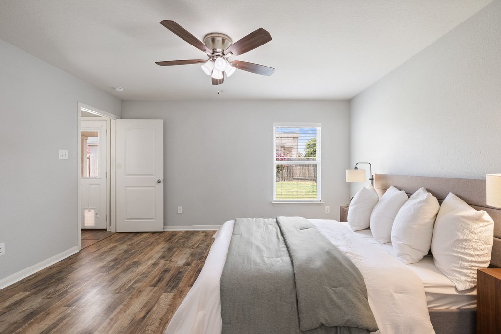 217 Farmer Lane Jarrell, TX 76537 - Photo 14 of 29 Wood-type flooring and a window offering backyard views define this peaceful primary bedroom.
