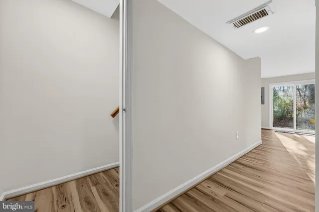 a view of a hallway with wooden floor and a bathroom