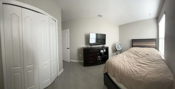 a bedroom with a bed and a flat tv screen on a dresser