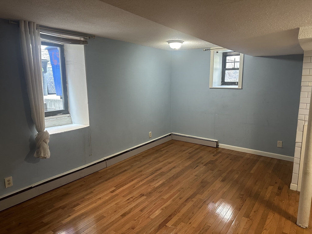 57 Brighton Avenue, Unit B Boston, MA 02134 - Photo 7 of 17 a view of an empty room with wooden floor and a window