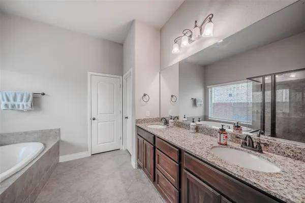 a bathroom with a granite countertop double vanity sink and a mirror