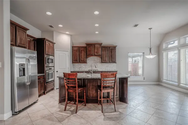 a dining area with stainless steel appliances a table and chairs