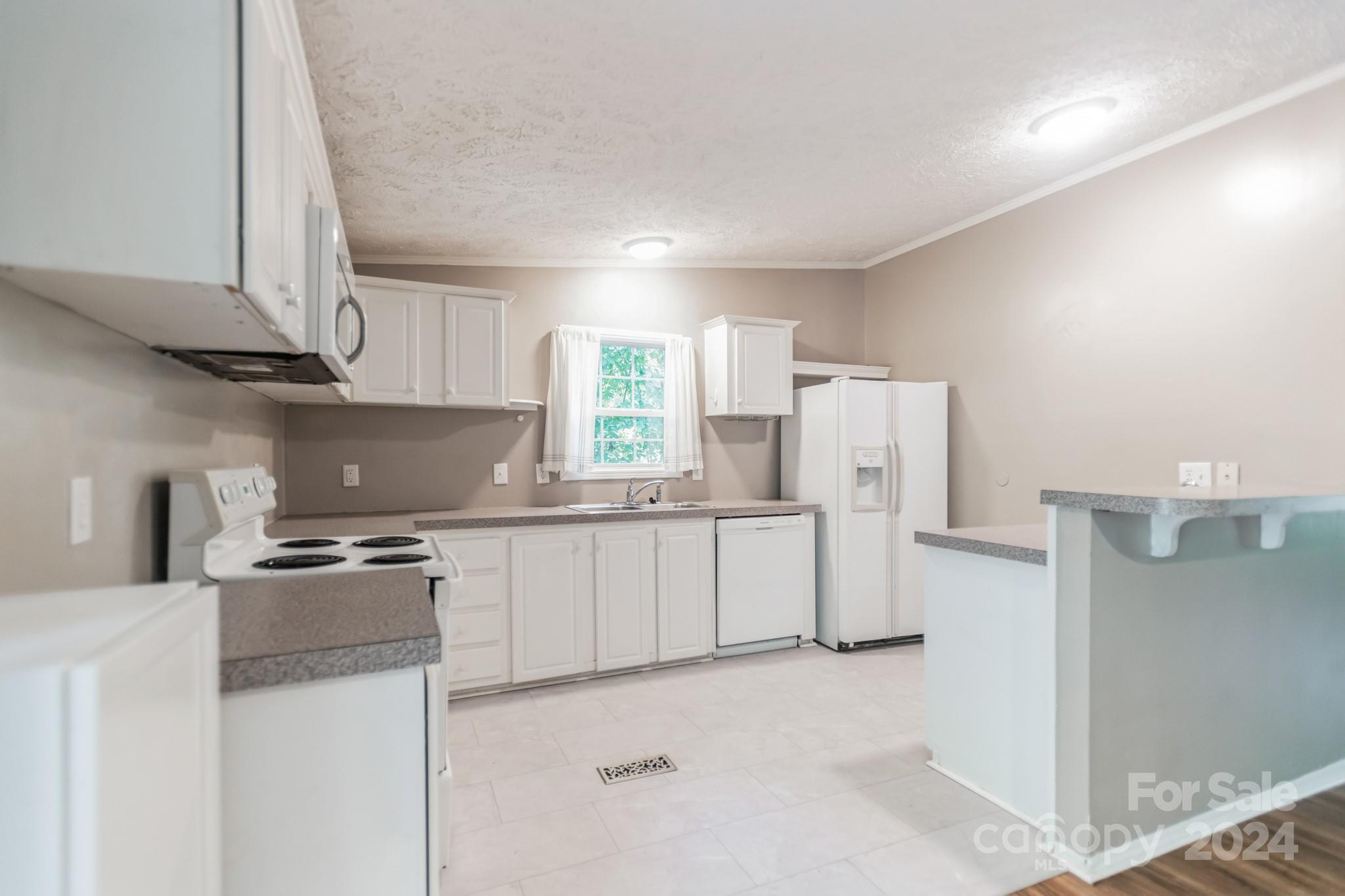 104 Cane Crest Circle Fairview, NC 28730 - Photo 4 of 29 a kitchen with white cabinets and white appliances