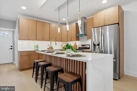 a kitchen with stainless steel appliances a refrigerator a sink a stove a dining table and chairs