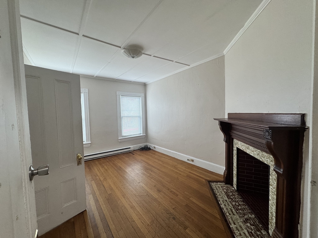 41 Pleasant Street, Unit 1 Attleboro, MA 02703 - Photo 4 of 7 a view of an empty room with wooden floor and a fireplace
