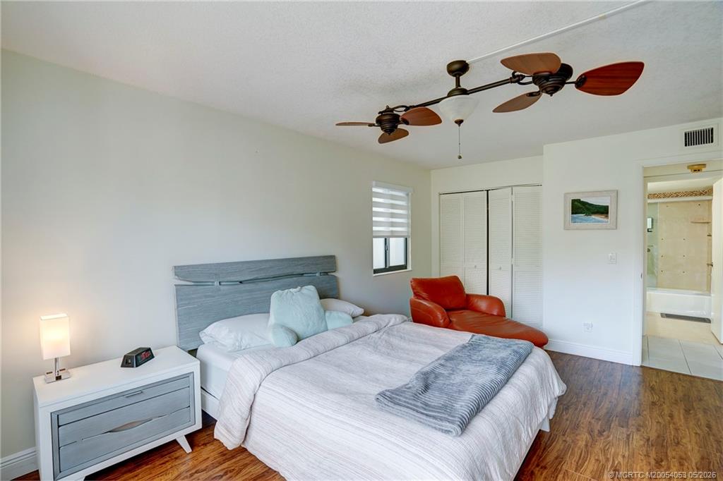10 Northeast Plantation Road, Unit 101 Jensen Beach, FL 34957 - Photo 42 of 53 a bedroom with a bed and wooden floor