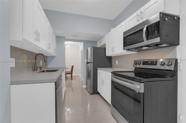 a kitchen with stainless steel appliances a stove microwave and sink