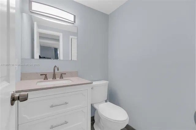 a bathroom with a toilet sink vanity and mirror