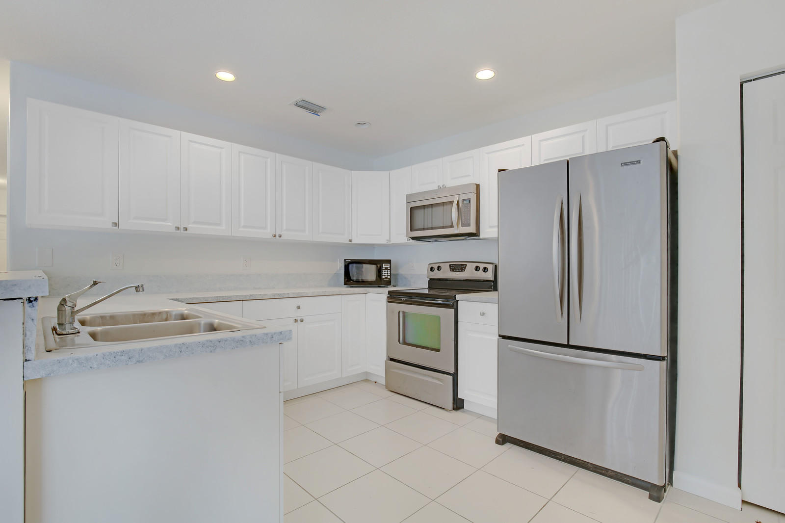 299 Palm Avenue Jupiter, FL 33477 - Photo 12 of 26 a kitchen with white cabinets and stainless steel appliances