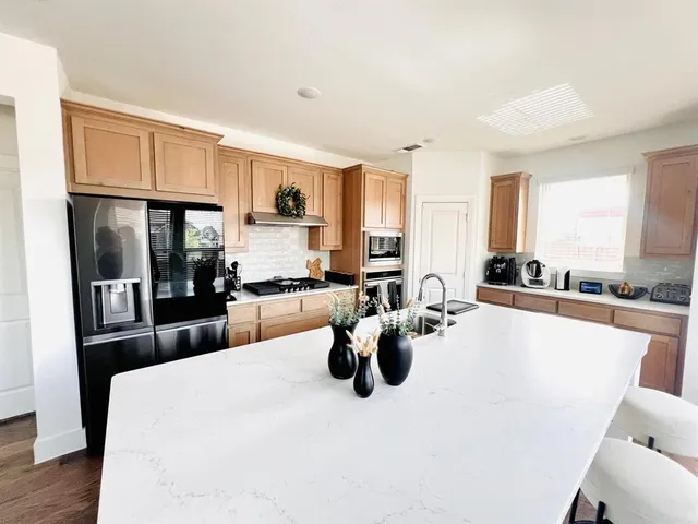a kitchen with a refrigerator a stove and a sink with wooden floor