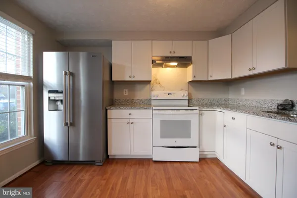a kitchen with cabinets wooden floor and stainless steel appliances