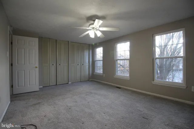 a view of an empty room with window and chandelier fan