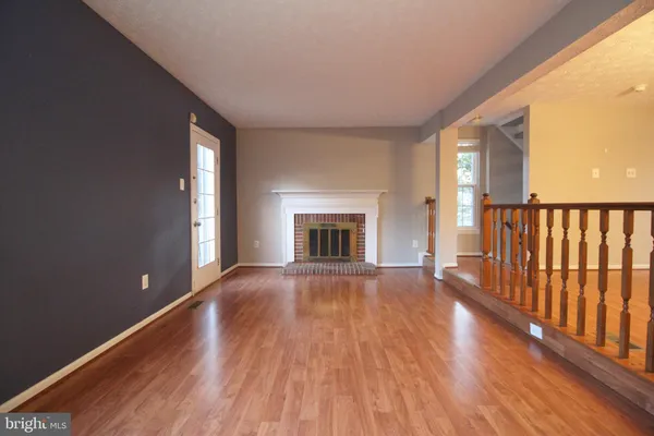 a view of empty room with wooden floor and fireplace