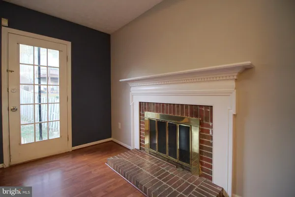 a view of an empty room with wooden floor fireplace and a window