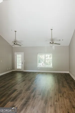 a view of empty room with wooden floor and fan