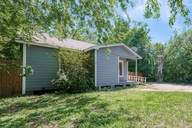 a view of a house with a yard plants and large tree