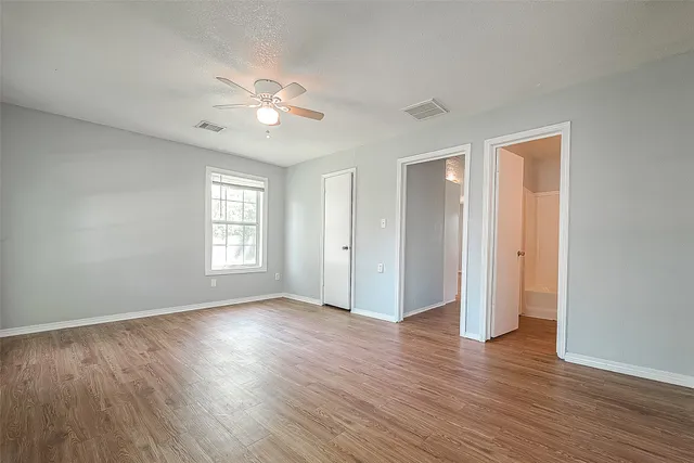 a view of an empty room with wooden floor and a window