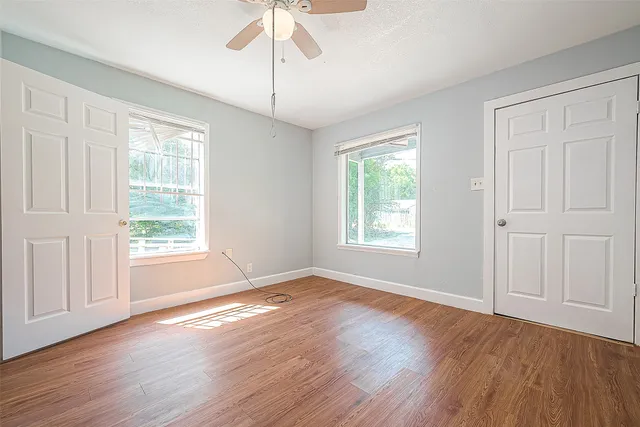 a view of an empty room with wooden floor and a window