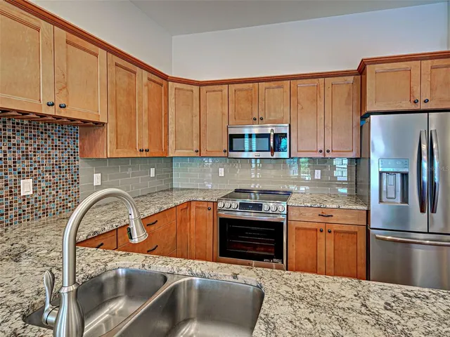 a kitchen with kitchen island granite countertop a sink cabinets and stainless steel appliances