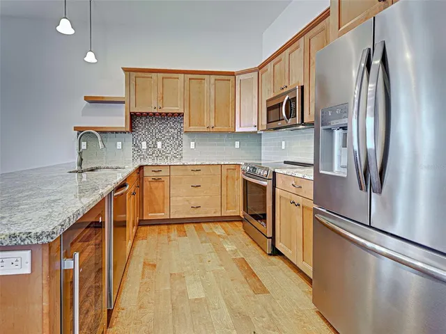 an empty room with wooden floor and kitchen view