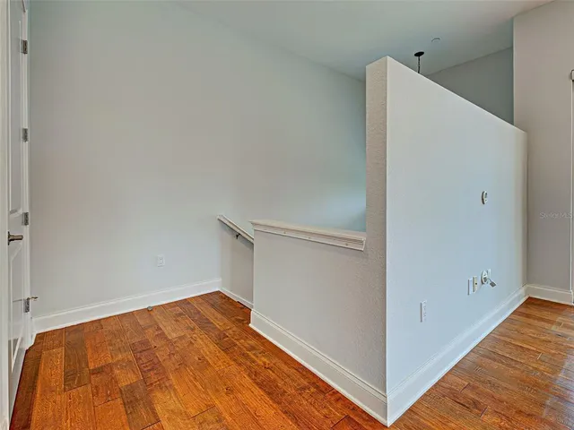 an empty room with wooden floor chandelier and windows