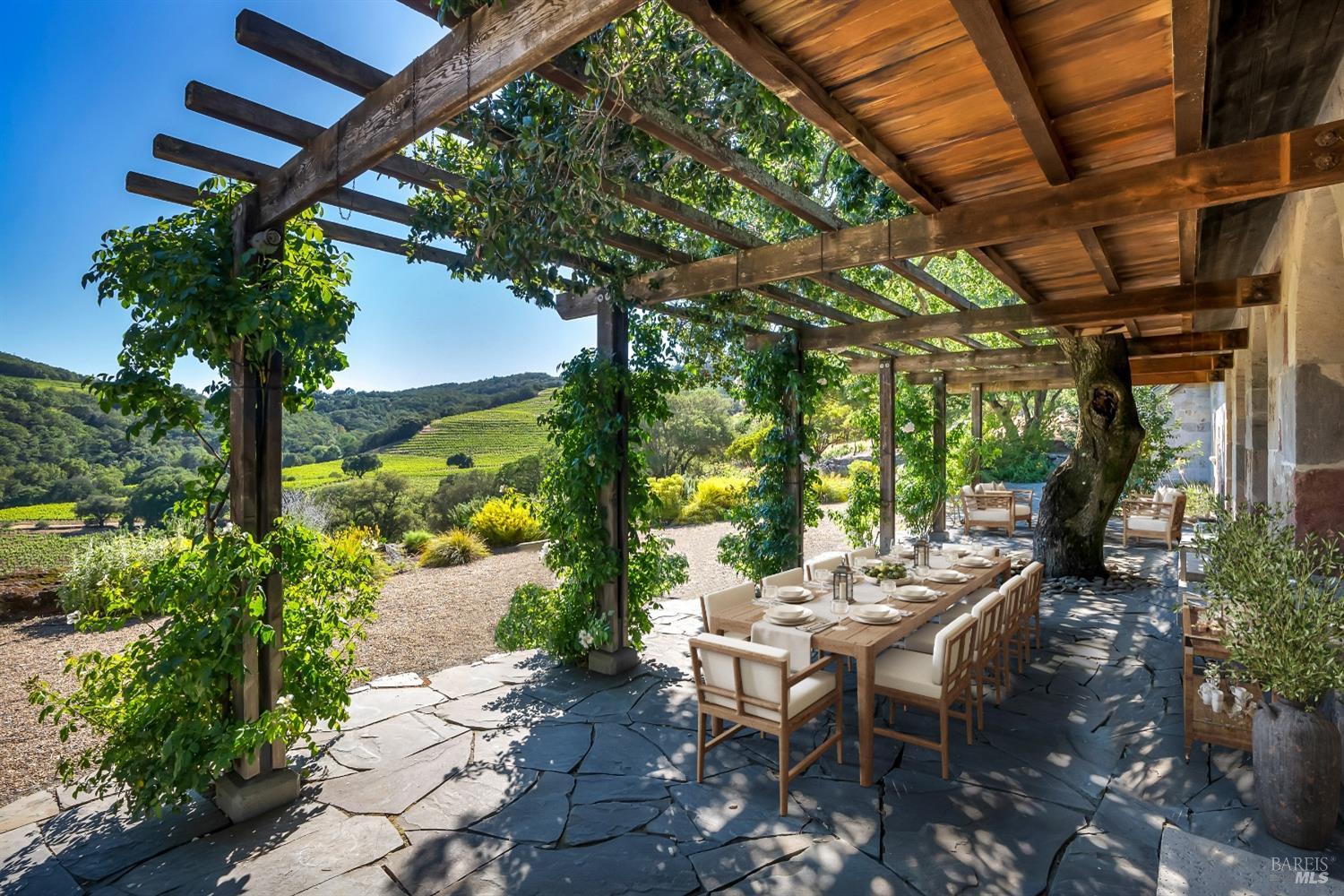 Stone house terrace with hillside vineyard views. Virtually Staged photo.