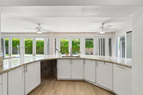 a view of a kitchen with a sink wooden cabinets and a window