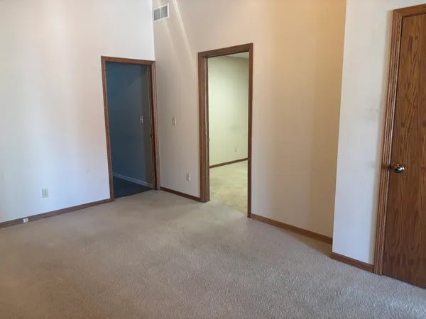 a view of an empty room with kitchen and window