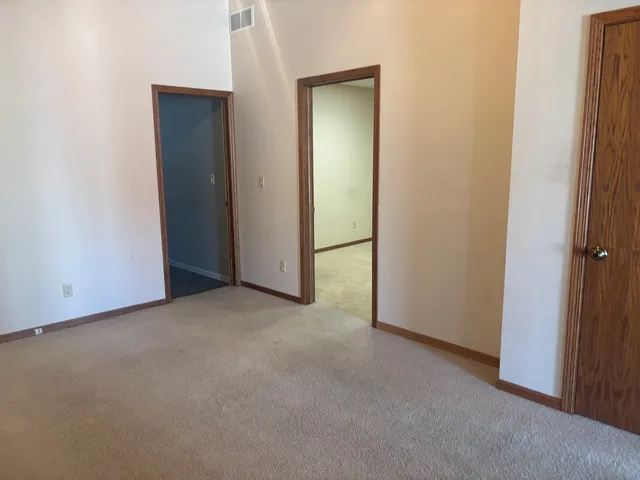 a view of an empty room with kitchen and window