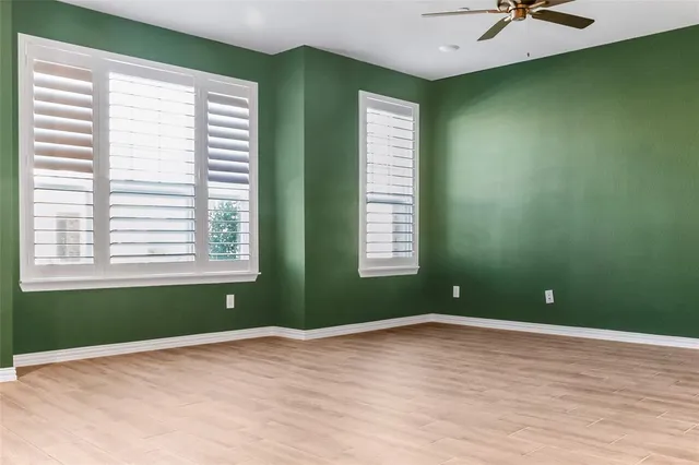 a view of empty room with windows and ceiling fan